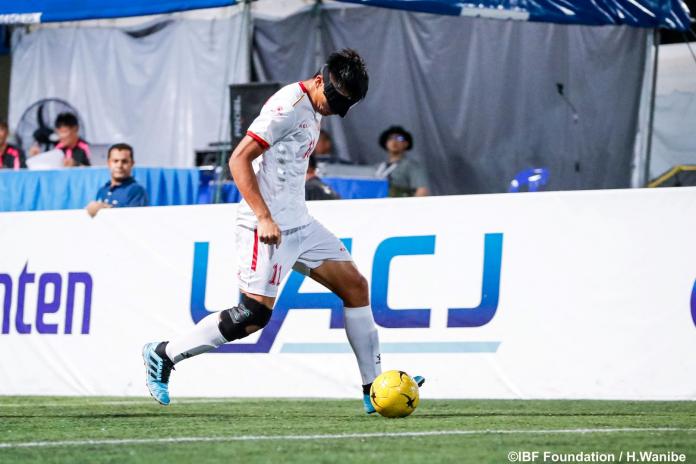 A male blind football dribbles the ball